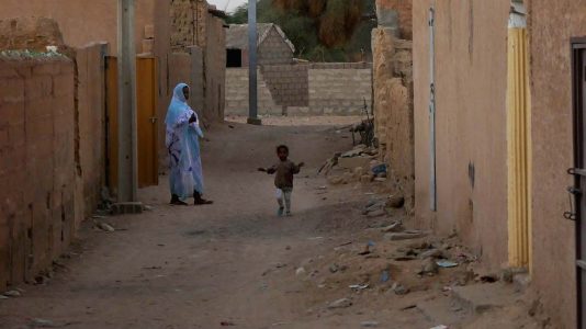 Mom Watching Kid Run Down Dusty Street in Atar - Mauritania